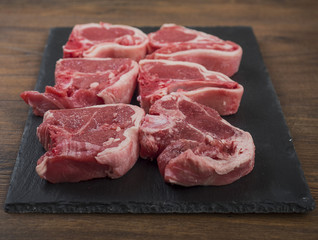 Close up of raw lamb chops on a board, front in focus, back out of focus.