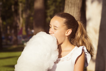 Girl eating cotton candy in a summer park 