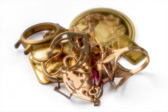 A scrap of gold. Old and broken jewelry, watches of gold and bullion on a white background in a soft focus.