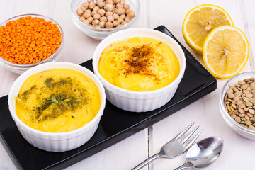 Two bowls with homemade hummus on white wooden background