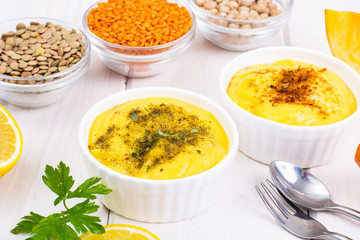 Two bowls with homemade hummus on white wooden background