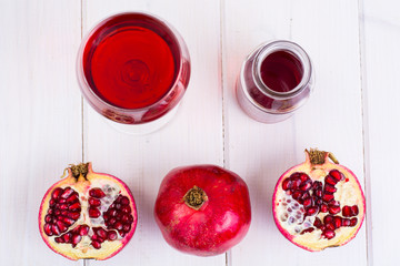 Pomegranate and juice in glass on white wooden background
