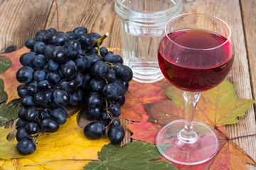 Composition with glass of red wine and grapes on wooden table close-up