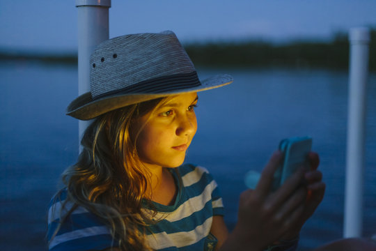 Teen Girl Texting on Cell phone While sitting on Dock