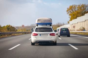 Fototapeta na wymiar white car with porter drives on a german motorway