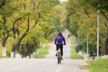 girl with a backpack on her back riding a bicycle