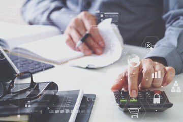 businessman hand working with finances about cost and calculator and latop with mobile phone on withe desk in modern office