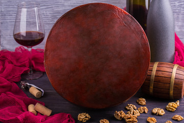 A round cheese without sticker with taste of walnuts and a glass of wine