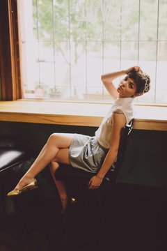 Girl sitting cross-legged at a bar by a window