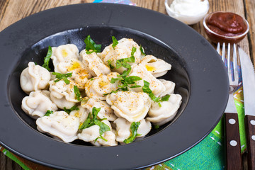 Black plate with boiled vegetarian vegetable dumplings