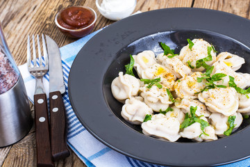 Black plate with boiled vegetarian vegetable dumplings