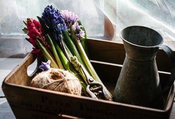 Hyacinth flowers, a jug and twine in a reclaimed wooden box.
