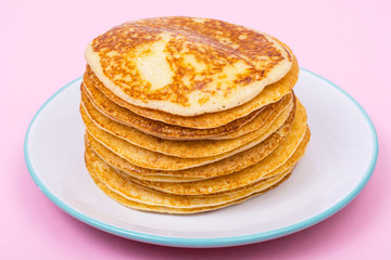 High stack of fried pancakes on pink background