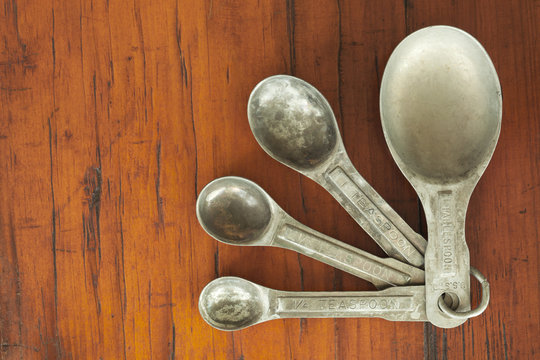 Old tarnished measuring spoons on a rough wood table