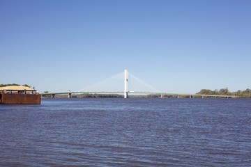 Obraz premium Blue skies over the choppy waters of the mississippi in front of a bridge and floating barge