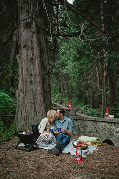 Couple On Romantic Camping Date Making Hot Chocolate And Eating Smores