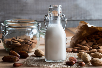 A bottle of almond milk with whole and shelled almonds