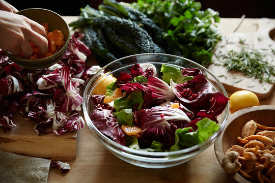 Woman making a radicchio and pomegranate, and orange salad