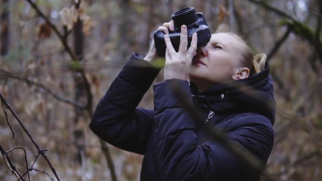 the photographer takes pictures of the autumn forest. cinematic shot, slow motion. the girl with the camera. landscape pictures