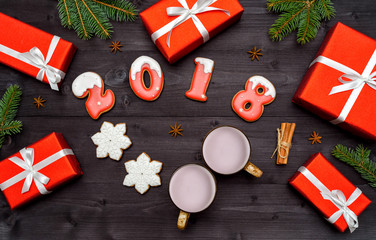 Christmas background with red gift boxes, fir tree branches, new year 2018 sign symbol, gingerbread cookies and two cups of cocoa,  cinnamon sticks and star anise. Flat lay, top view