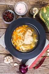 Soup with chicken, pumpkin and noodles on wooden table