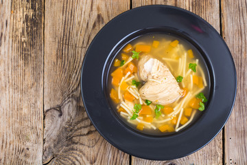 Soup with chicken, pumpkin and noodles on wooden table