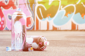 Several used spray cans with pink and white paint and caps for spraying paint under pressure is...