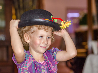 Mała dziewczynka przebiera się w duży kapelusz. Piękny uśmiech.