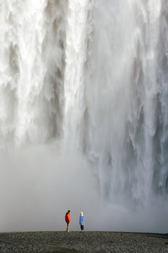 Iceland, Skogar, Skogafoss Falls, southern Iceland. Visitors standing in front of the Falls. Skogafoss is one of 20 waterfalls found along the Skogar River. The waterfall is 60 meters high.