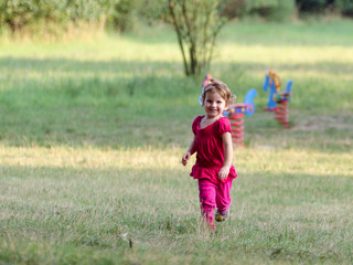 Dziewczynka biegnie na placu zabaw w letni dzień . - obrazy, fototapety, plakaty