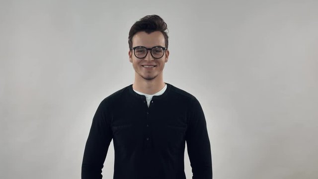 Attractive young man posing looking at camera smiling. Portrait happy smart caucasian millennial with black hair wearing casual shirt and eyeglasses