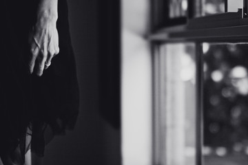 Hand of woman, wearing a black tulle dress, standing near a window