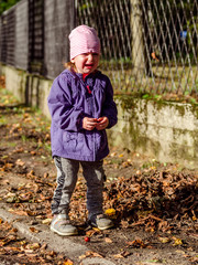 Mała dziewczynka płacze na spacerze po jesiennym parku.