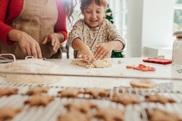 Mother teaching daughter to make cookies for Christmas.