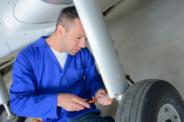 Mechanic with screwdriver working on aircraft landing gear
