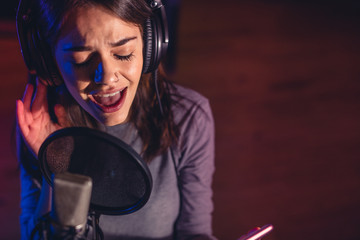 Obraz na płótnie Canvas Singer singing a song in the recording studio
