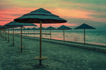 Adriatic coast sunset with beach umbrellas.View of the beach of Porec, during sunset with dark, cloudy sky. Croatia