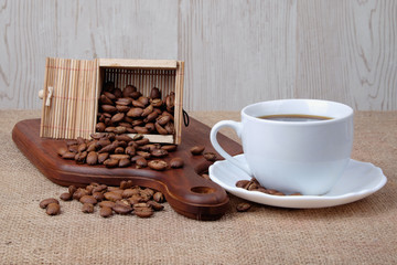 Cup of dark coffee with coffee beans on wooden cutting board . Relax time concept.