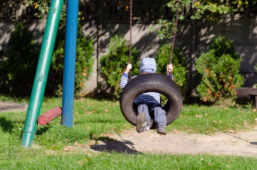 Mały chłopiec bawi się na placu zabaw w jesienny słoneczny dzień.