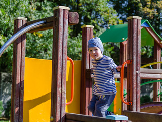 Fototapeta na wymiar Mały chłopiec bawi się na placu zabaw w jesienny słoneczny dzień.