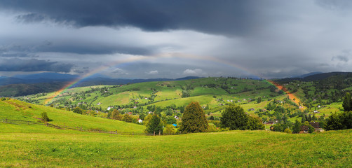 Fototapeta na wymiar Rainbow over the villiage at the Carpatian mountains