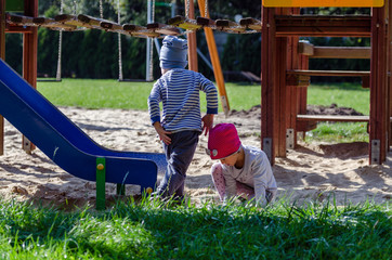 Rodzeństwo dzieci bawi się na planu zabaw w jesienny słoneczny dzień.