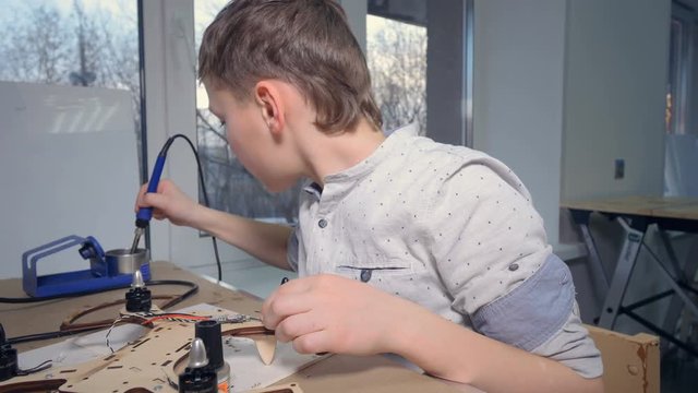 A young kid is soldering his modern flying gadget