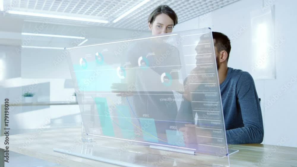 Poster in the near future male and female office workers discuss graphical statistic shown on transparent c