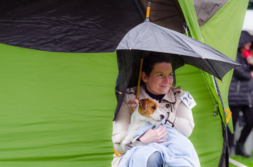 Szczeniak Jack Russell terrier na rękach swojej właścicielki. Zdjęcie w plenerze w wietrzny deszczowy jesienny dzień. - obrazy, fototapety, plakaty