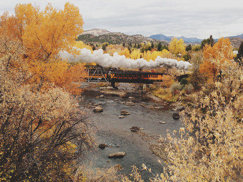 Fall Steam Train Crossing River on Bridge