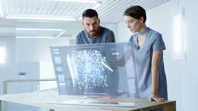 In the Near Future Male and Female Computer Engineers Talk While Working on the Transparent Display Computer. Screen Shows Interactive Neural Network, Artificial Intelligence Project.