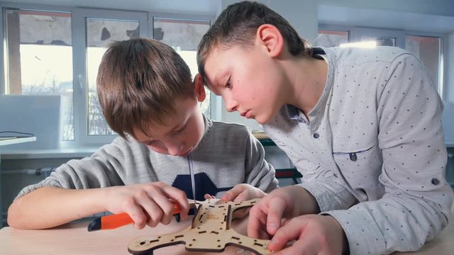 Two boys are finishing their wooden drone model