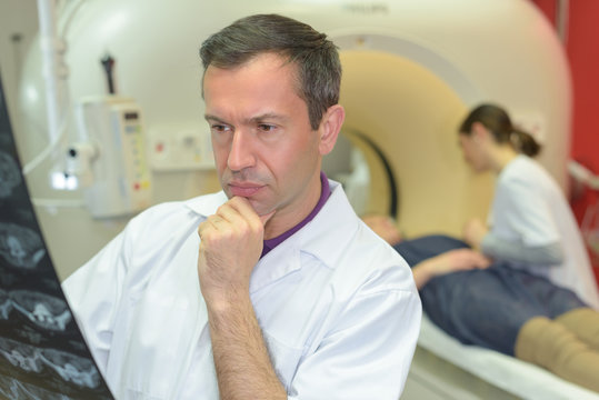 doctor looking at xrays patient entering mri scanner in background