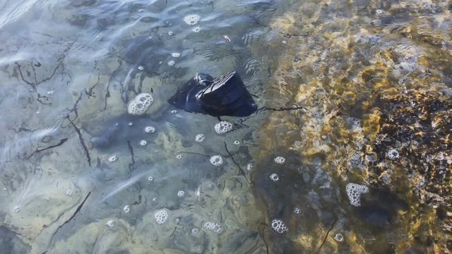 Unrecognizable boot floats on the surface of water in the sea